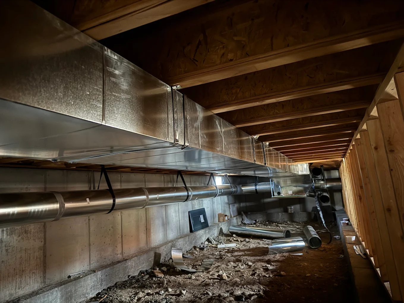 New sheet metal trunk line and round duct runs installed in a crawlspace